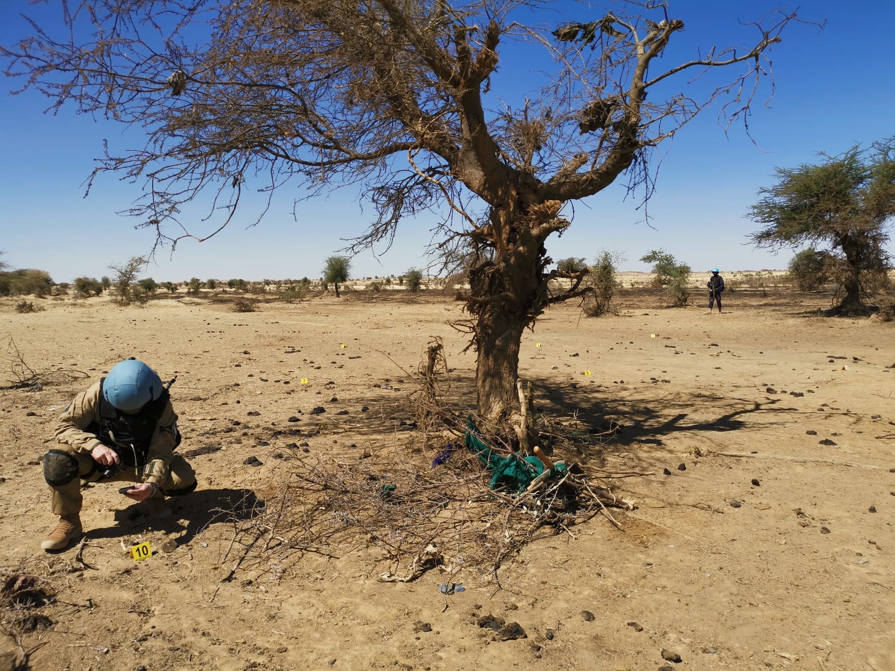 Henkilö kumartuneena tutkimaan maassa olevia jälkiä Malissa.